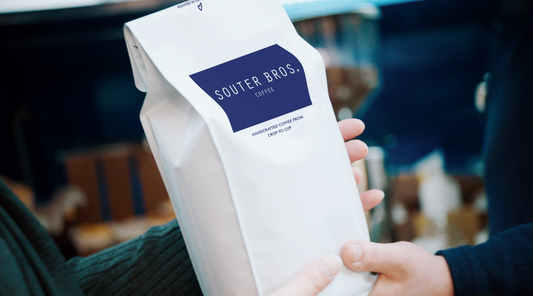 Speciality Coffee in white bag with Souter Bros label changing hands